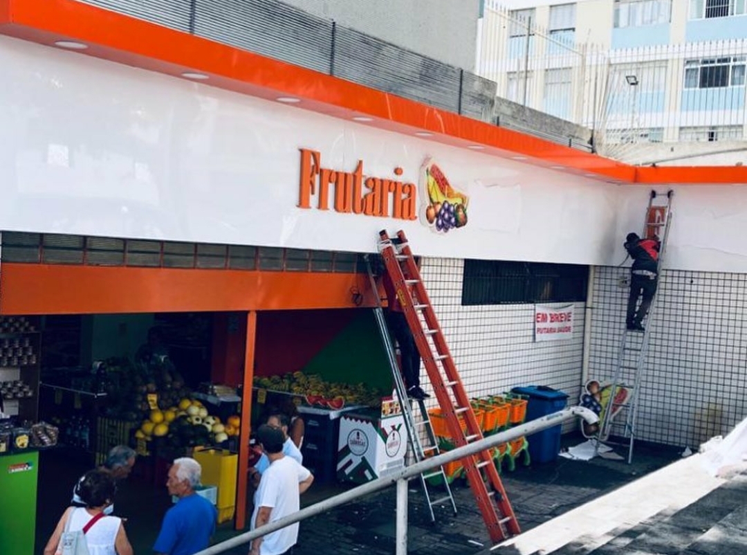Fachada em ACM branco e laranja com letras-caixa de frutaria
